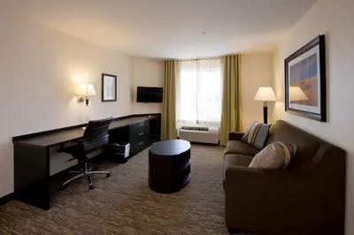 a living room with a couch and a desk in a hotel room at Candlewood Suites Greeley by IHG in Greeley