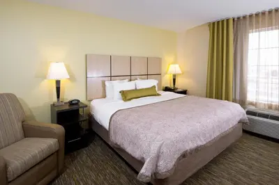 a hotel room with a large bed and a couch at Candlewood Suites Greeley by IHG in Greeley