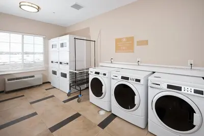 a laundry room with three washing machines and a window at Candlewood Suites Greeley by IHG in Greeley