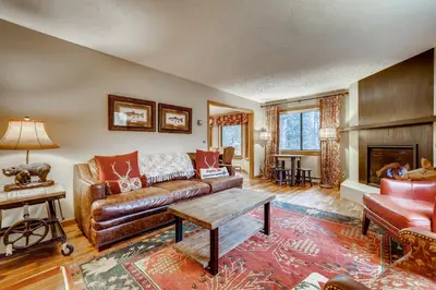 a living room with a leather couch and a table at Casa de Montagne Home: High-End Log Home, Downtown Frisco in Frisco