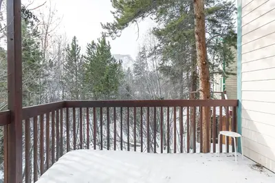 a wooden balcony with a bench and snow on it at Solitude Station Home: Walk to Downtown in Frisco