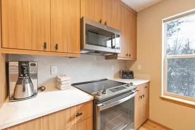 a kitchen with wooden cabinets and a stove top oven at Solitude Station Home: Walk to Downtown in Frisco