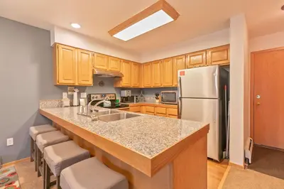 a kitchen with wooden cabinets and a white refrigerator at Lagoon Royal Townhome: Mountain Views Meet Modern Comforts in Frisco