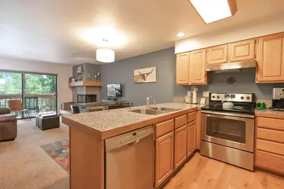 a kitchen with wooden cabinets and stainless steel appliances at Lagoon Royal Townhome: Mountain Views Meet Modern Comforts in Frisco