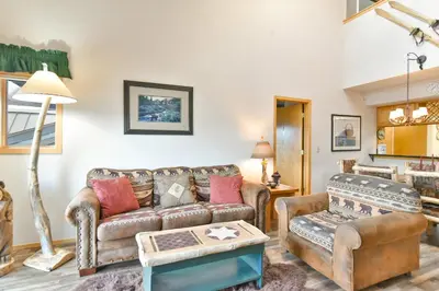 a living room with a couch and a table at Lake Forest Summit Condo: Great Penthouse Views in Frisco