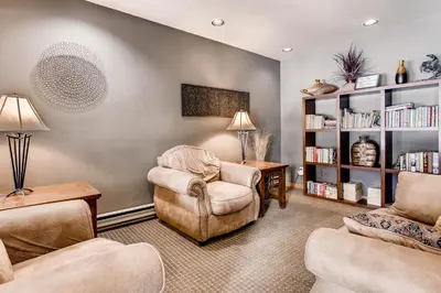 a living room with two chairs and a book shelf at Cedar Lodge Peak One Studio Condo: Downtown Frisco in Frisco