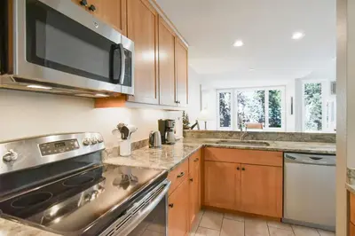 a kitchen with wooden cabinets and a stainless steel appliance at River Glen Brookside Condo: Fantastic Frisco Location in Frisco