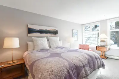 a bedroom with a bed and two windows at River Glen Brookside Condo: Fantastic Frisco Location in Frisco