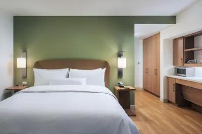 a bedroom with a large white bed and a kitchen at Element Denver Downtown East in Denver