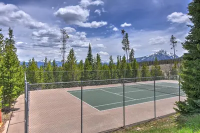 a tennis court with trees and mountains in the background at Timber Ridge Retreat in Silverthorne
