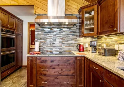 a kitchen with wooden cabinets and a brick wall at Herondale Luxury Home Home in Estes Park