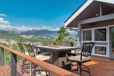 a balcony with a table and chairs and mountains at Herondale Luxury Home Home in Estes Park