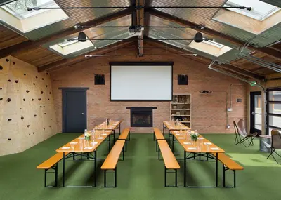 a large room with long tables and a large screen at Basecamp Boulder in Boulder