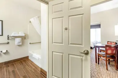 a bathroom with a door and a table with a chair at Quality Inn & Suites University Fort Collins in Fort Collins