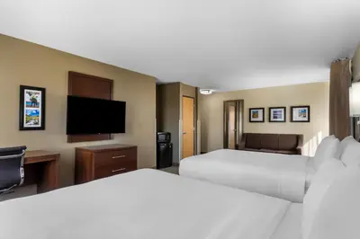 a hotel room with two beds and a flat screen tv at Comfort Inn & Suites Greeley in Greeley