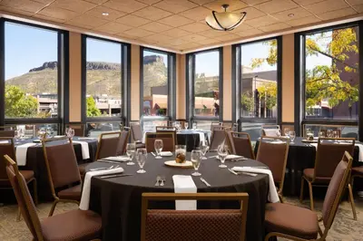 a dining room with tables and chairs and windows at The Golden Hotel, an Ascend Collection Hotel in Golden