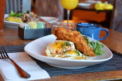 a plate of food with fried chicken and greens on a table at The Golden Hotel, an Ascend Collection Hotel in Golden