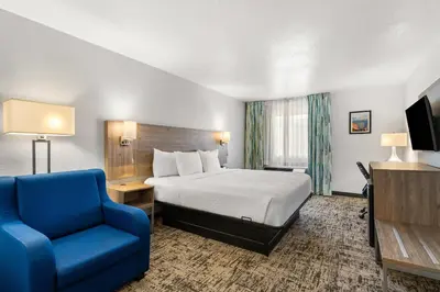 a hotel room with a bed and a blue chair at Quality Inn & Suites Denver International Airport in Denver