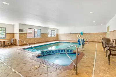 a pool in a hotel room with tables and chairs at Comfort Suites Longmont in Longmont