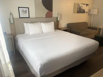 a bedroom with a white bed and a chair at Spark by Hilton Lakewood Denver Southwest in Lakewood