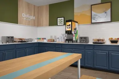 a kitchen with blue cabinets and a wooden table at Spark by Hilton Lakewood Denver Southwest in Lakewood