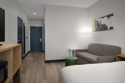 a room with a bed and a couch and a tv at Spark by Hilton Lakewood Denver Southwest in Lakewood