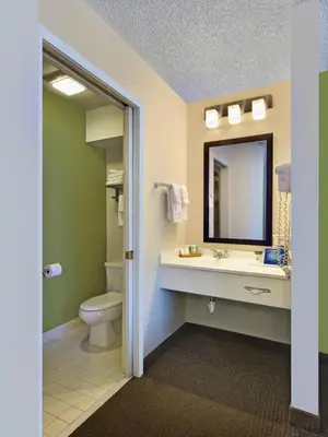 a bathroom with a toilet and a sink and a mirror at Baymont by Wyndham Fort Collins in Fort Collins