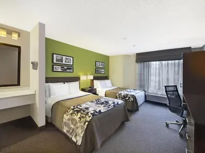 a hotel room with two beds and a flat screen tv at Baymont by Wyndham Fort Collins in Fort Collins