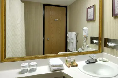 a bathroom with a sink and a large mirror at Baymont by Wyndham Fort Collins in Fort Collins