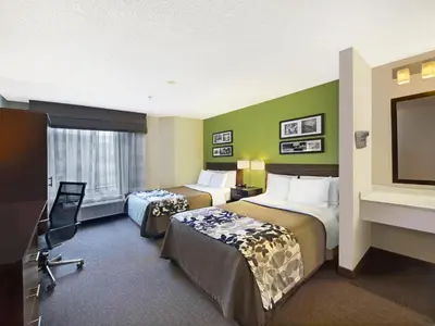 a hotel room with two beds and a flat screen tv at Baymont by Wyndham Fort Collins in Fort Collins
