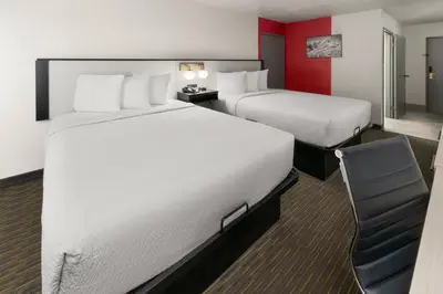 a hotel room with two beds and a chair at SYLO Hotel Denver Airport, a Ramada by Wyndham in Aurora