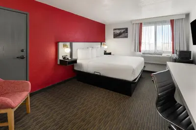 a hotel room with a bed and a red wall at SYLO Hotel Denver Airport, a Ramada by Wyndham in Aurora