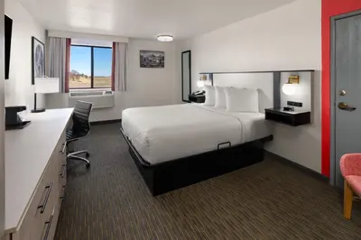 a hotel room with a large bed and a desk at SYLO Hotel Denver Airport, a Ramada by Wyndham in Aurora