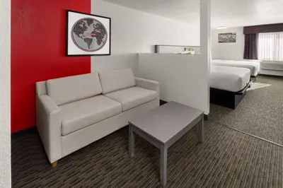 a living room with a couch and a bed at SYLO Hotel Denver Airport, a Ramada by Wyndham in Aurora