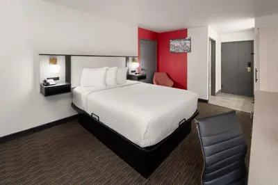 a hotel room with a bed and a chair at SYLO Hotel Denver Airport, a Ramada by Wyndham in Aurora