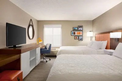 a hotel room with two beds and a flat screen tv at Hampton Inn Denver-West/Golden in Golden
