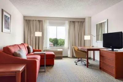 a hotel room with a couch and a desk and a television at Hampton Inn & Suites Denver-Cherry Creek in Denver