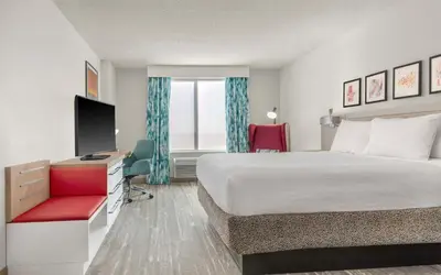 a hotel room with a bed and a desk with a television at Hilton Garden Inn Denver Airport in Aurora