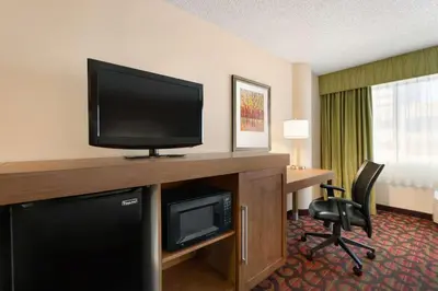 a hotel room with a desk and a flat screen tv at Hampton Inn Denver West Federal Center in Lakewood