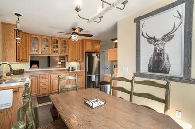 a kitchen with a wooden table with a deer picture on the wall at Aspen Grove Getaway - EV #3196 in Estes Park