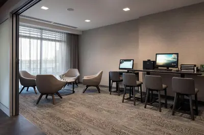a waiting room with chairs and a table and a television at Courtyard Denver Airport at Gateway Park in Denver