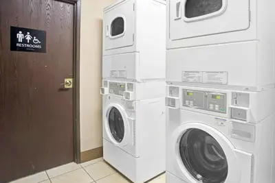 two washing machines are stacked next to a door at Super 8 by Wyndham Wheat Ridge/Denver West in Wheat Ridge