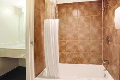 a bathroom with a shower with a tub and a sink at Super 8 by Wyndham Wheat Ridge/Denver West in Wheat Ridge