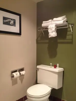 a bathroom with a white toilet and some towels at Super 8 by Wyndham Wheat Ridge/Denver West in Wheat Ridge