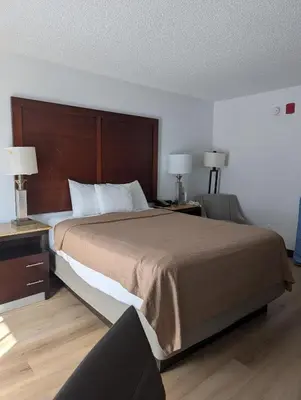 a bedroom with a large bed with two tables and two lamps at Plaza Hotel Denver Central in Denver