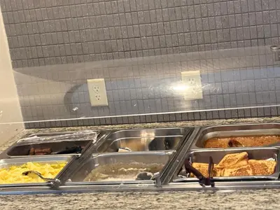 a buffet line with many trays of food at Plaza Hotel Denver Central in Denver