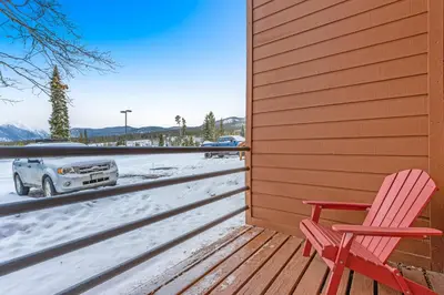 a deck with a red chair and a car in the snow at 2 Bed 2 Bath Apartment in Summit County in Silverthorne