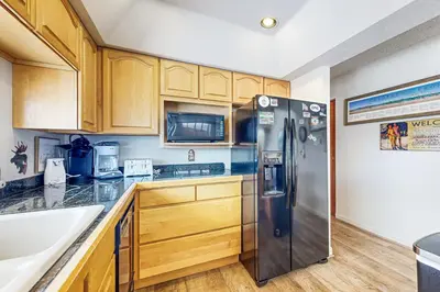 a kitchen with a stainless steel refrigerator and wooden cabinets at 4 Bed 4 Bath Studio Apartment in Fraser in Fraser