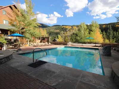 a swimming pool in a resort with a mountain in the background at River Run Village in Keystone
