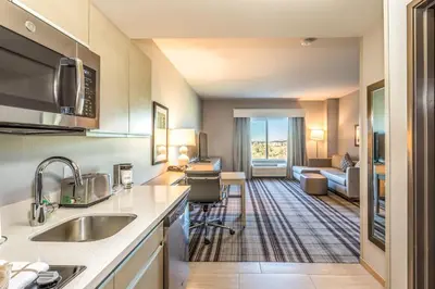 a kitchen with a sink and a living room at Hawthorn Extended Stay by Wyndham Loveland in Johnstown